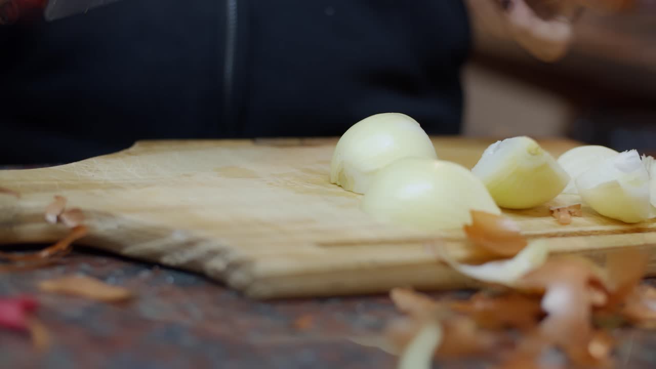 Woman's hands cutting an onion at home with painted nails - Warm house vibes - cooking at home - 4k at 60fps (slowmotion)