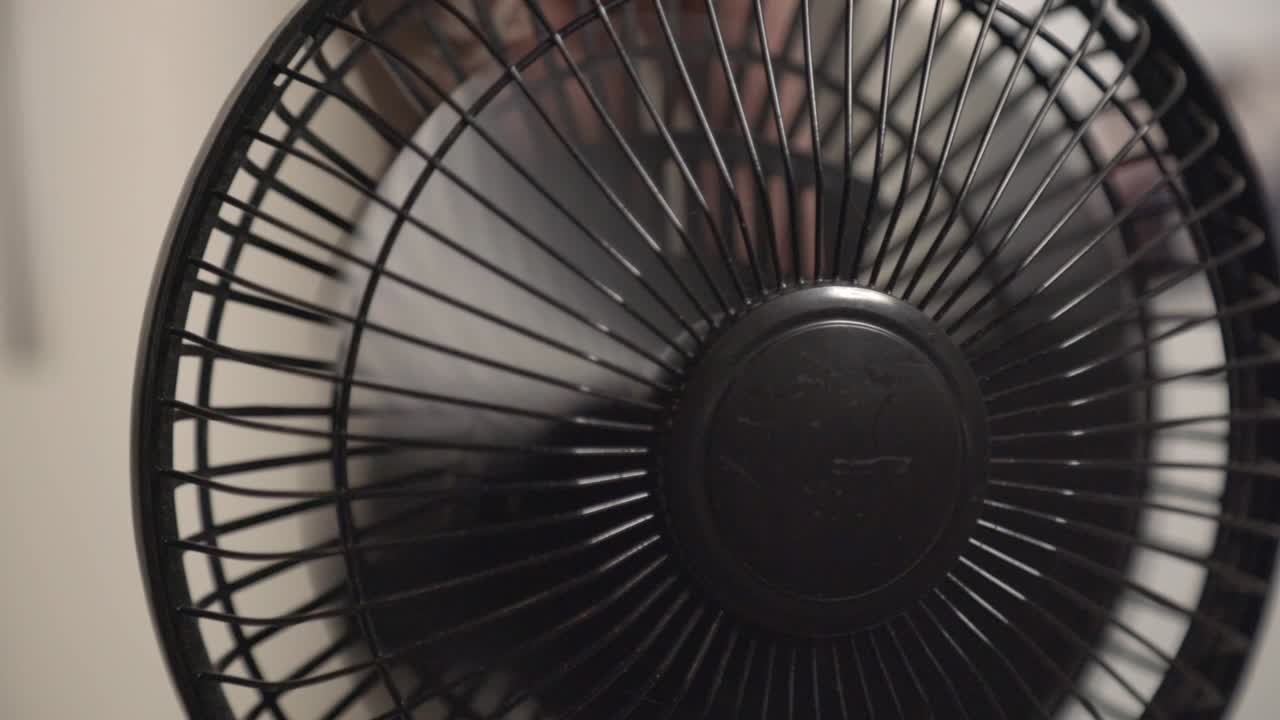 Mão desligando o mini ventilador preto — Close-up