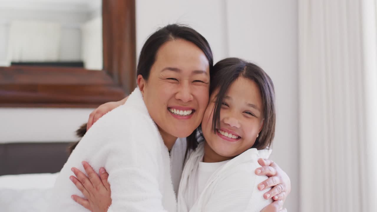 행복한 아시아인 어머니와 딸이 옷을 입고 포옹하고 재미를 느끼는 비디오