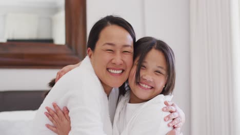 Video-Einer-Glücklichen-Asiatischen-Mutter-Und-Tochter-In-Roben,-Die-Sich-Umarmen-Und-Spaß-Haben