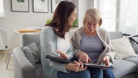 video de madre e hija adulta mirando un álbum de fotos