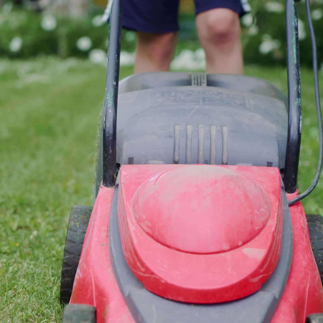 Boy mowing the lawn. Close-up