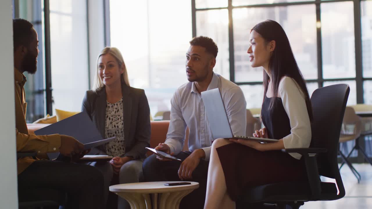 Video of happy diverse colleagues in discussion at informal office meeting at sundown