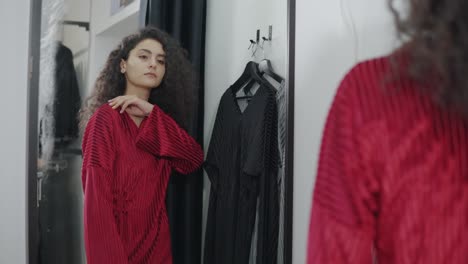 woman trying on a red dress in a fitting room