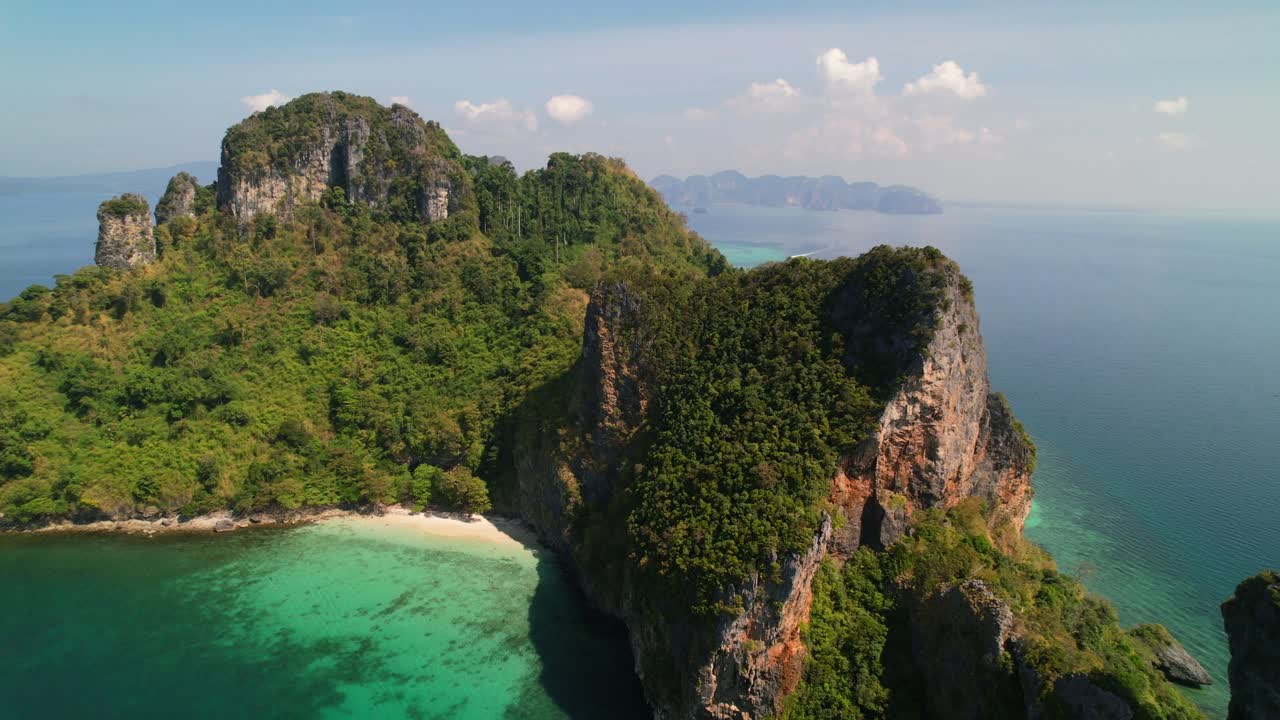 Drone aereo che effettua una panoramica verso destra su Ko Kai, circondata da spiagge di sabbia bianca incontaminata e una lussureggiante foresta nella tropicale Krabi, Thailandia, con un oceano blu turchese in una giornata di sole