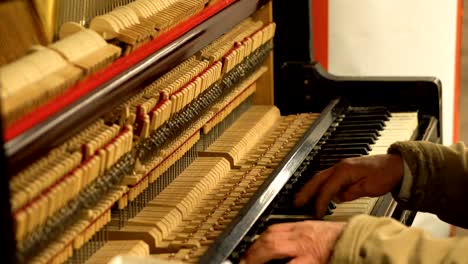 manos de un anciano en el metro subterráneo tocando el piano con el mecanismo abierto og cuerdas y martillos