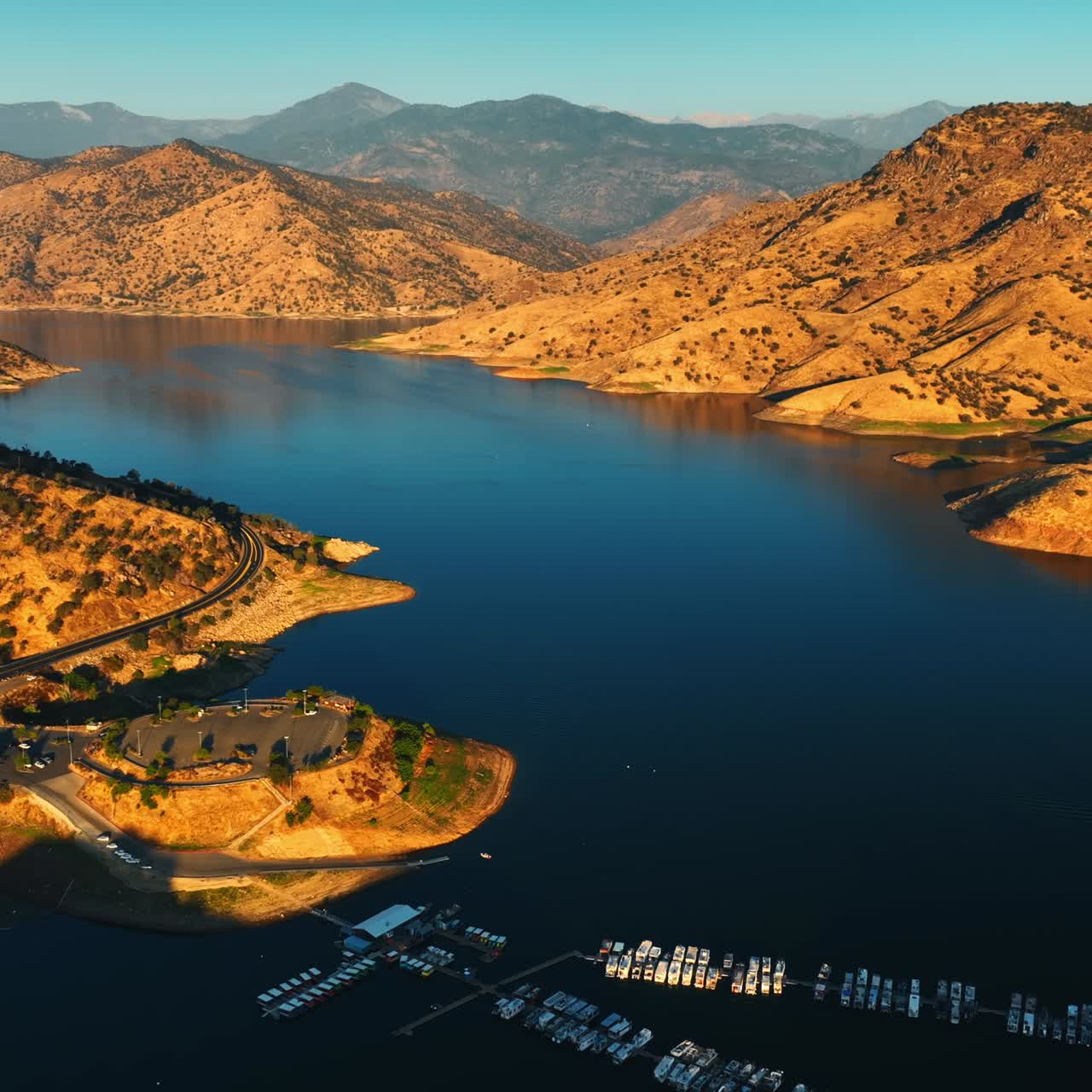 Multiple yacht at the dock on the calm lake. Gorgeous sunlit bare mountains around the lake. Top view