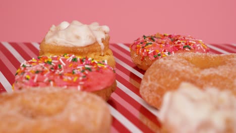 deliciosos donuts rosados y blancos con crema y chispas: la cámara cambia de enfoque a medida que se desliza hacia afuera