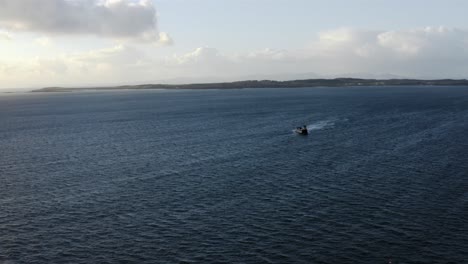 AERIAL---Ferry-ship-traveling-to-the-Isle-of-Gigha,-Kintyre,-Scotland,-forward