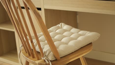 wooden chair with beige cushion at a light wood desk