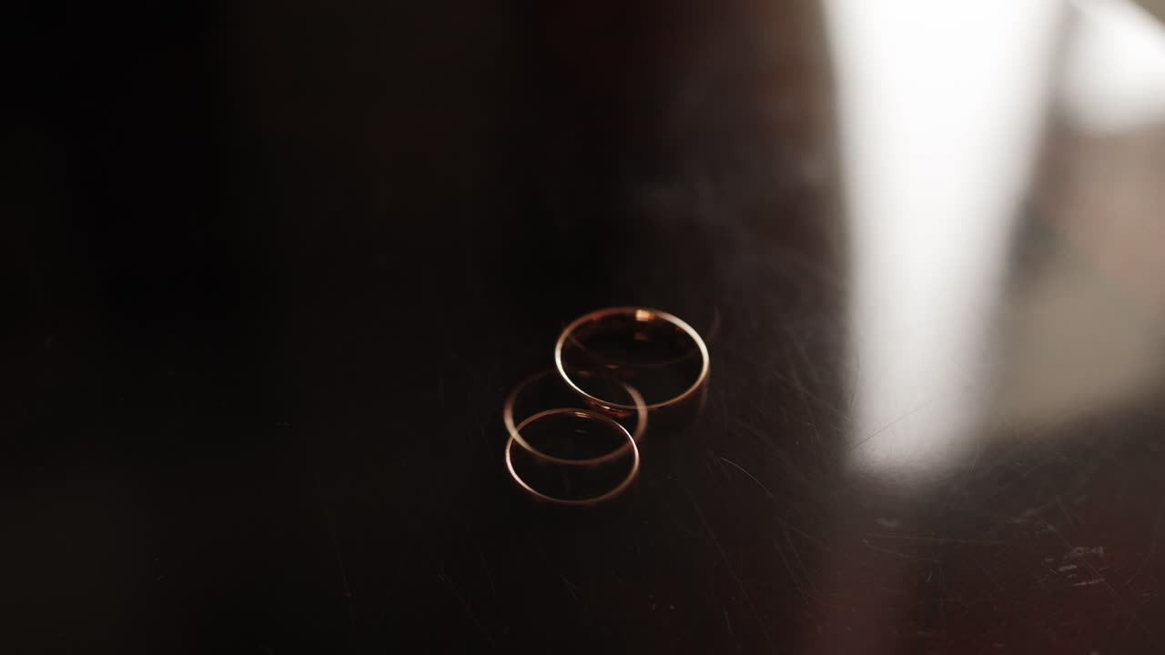 dos alianzas de boda doradas colocadas juntas con luz tenue