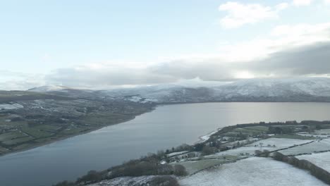 vista panorámica del lago de bendición y las montañas de wicklow cubiertas de nieve durante el invierno en irlanda, - antena