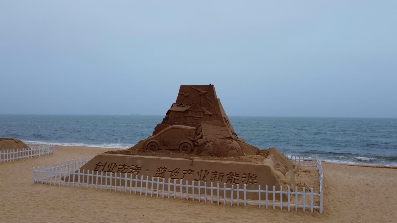 Beach sand sculpture pyramid castle with electric vehicle and renewable energy theme - visible car charging closeup aerial view