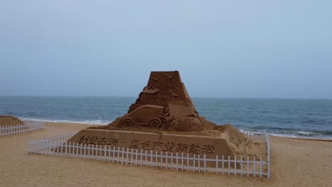 beach sand sculpture pyramid castle with electric vehicle and renewable energy theme - visible car charging closeup aerial view