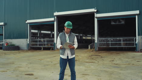 Agriculture-worker-writing-clipboard-at-cowshed.-Smiling-supervisor-posing-alone