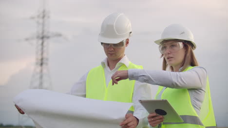 engineers in uniform working with a laptop near transmission lines.