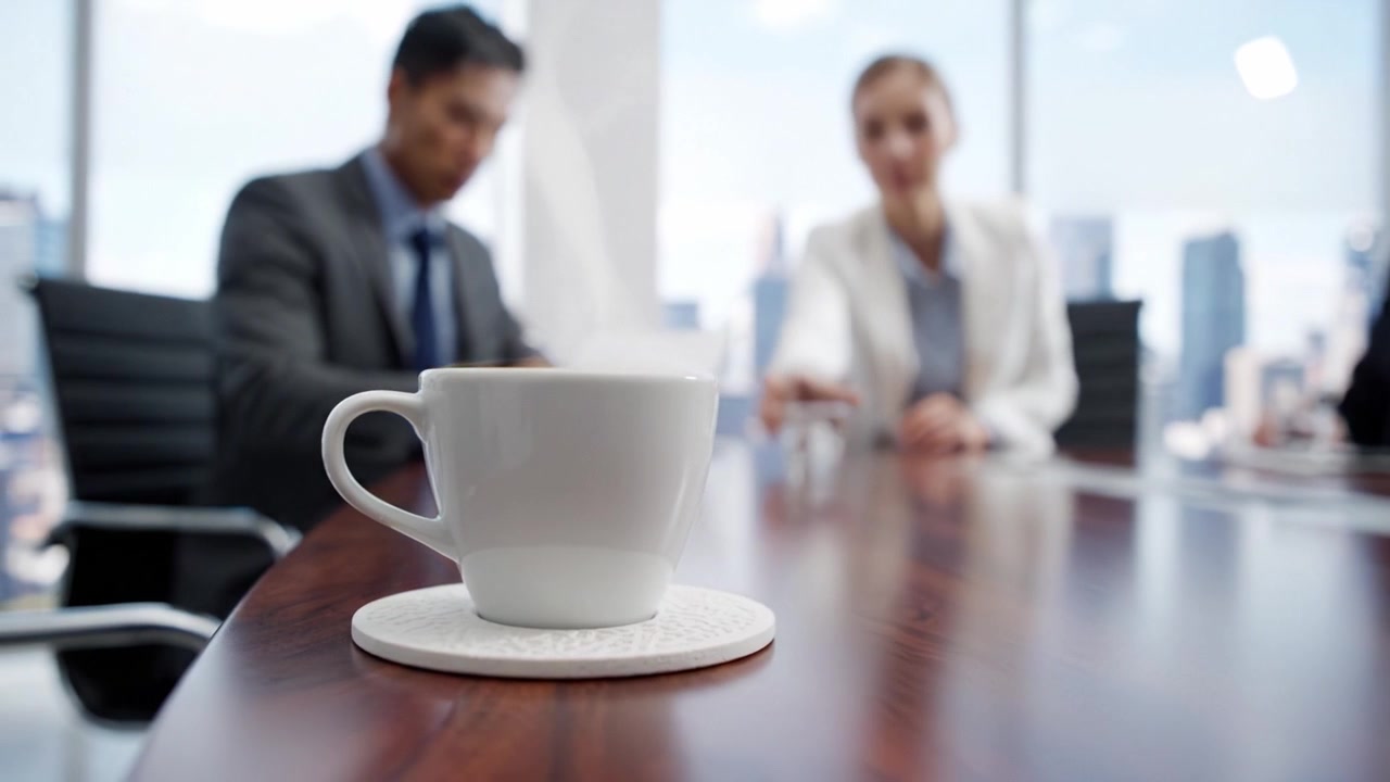 Atmosfera de reunião de negócios com foco na xícara de café em um ambiente de escritório moderno, apresentando colegas engajados em discussão e contemplação sobre assuntos profissionais.