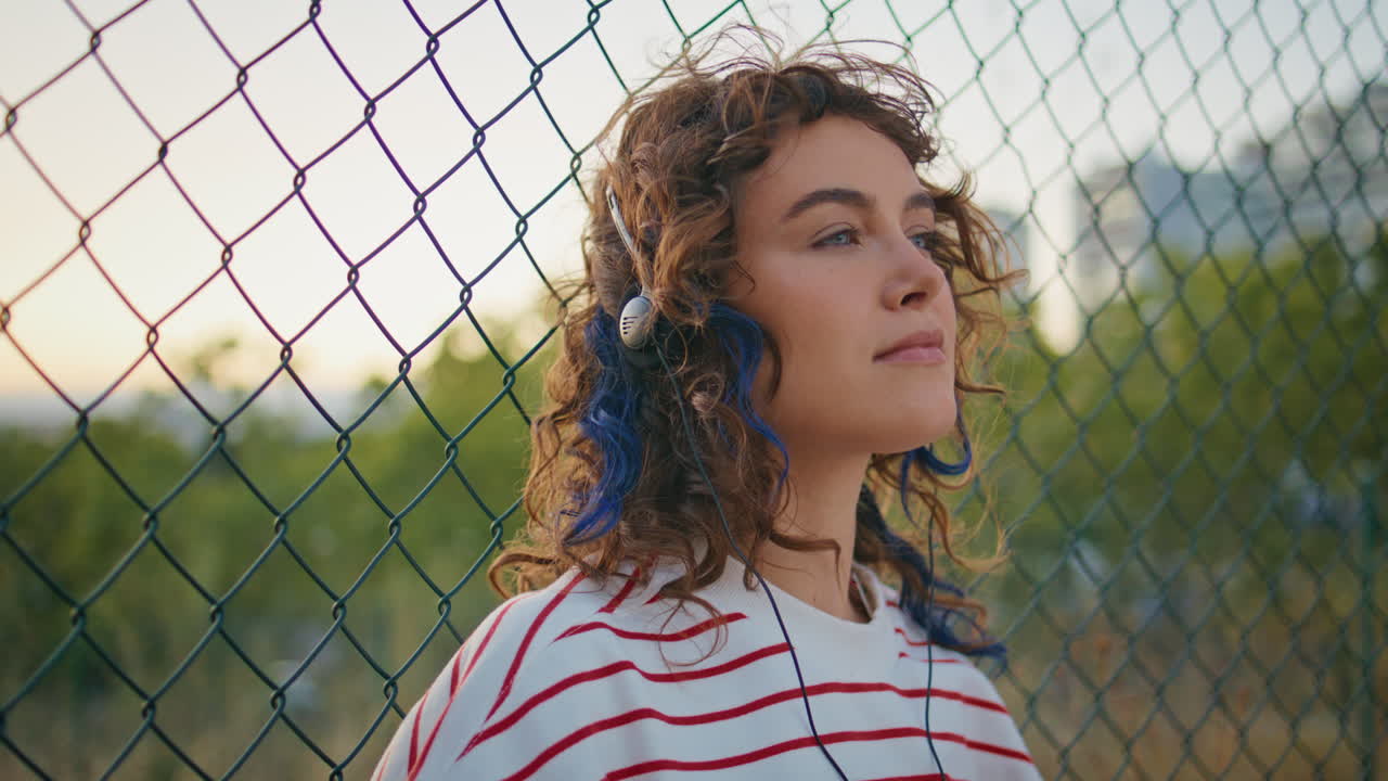 Dreamy earphones girl enjoying music on evening street close up. Woman listening