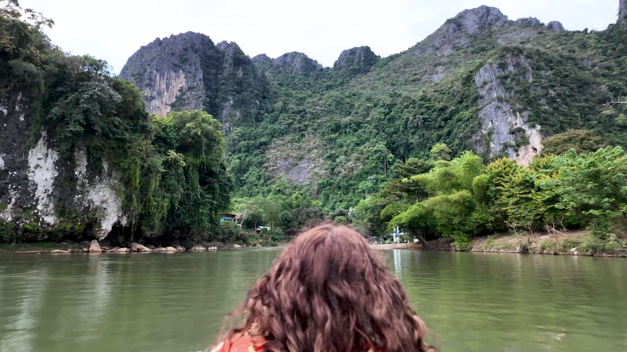 Woman travelling by boat on a river, exploring mountains and nature in Laos