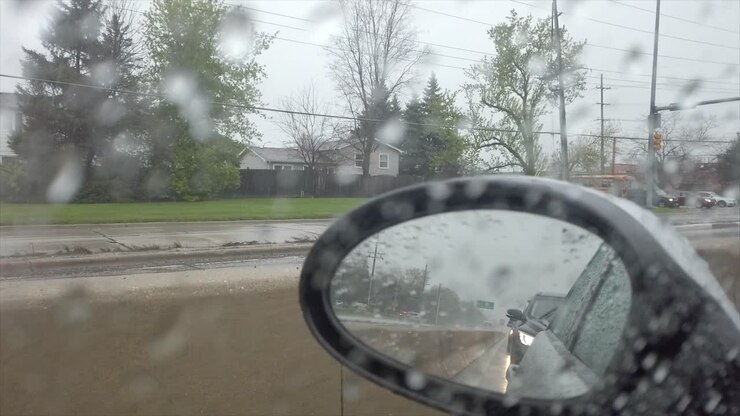 Looking in side mirror on a rainy day while driving