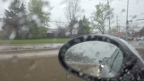 Looking-in-side-mirror-on-a-rainy-day-while-driving
