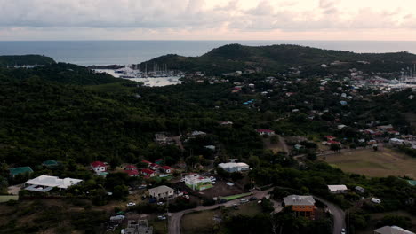 Toma-Aérea-De-La-Puesta-De-Sol-En-Puerto-Inglés-En-Antigua,-Caribe-Con-Vistas-De-Yates,-Veleros,-Puerto-Deportivo,-Bahía-Y-Acantilados