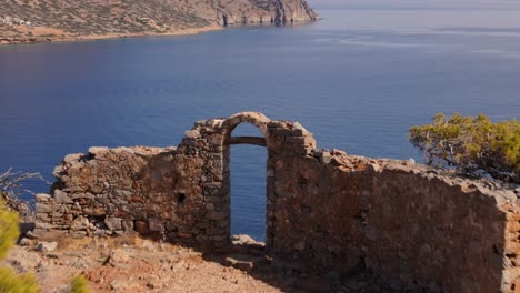 las ruinas de la antigua entrada del arco miran a la impresionante bahía azul en la isla de spinalogka, creta, grecia.