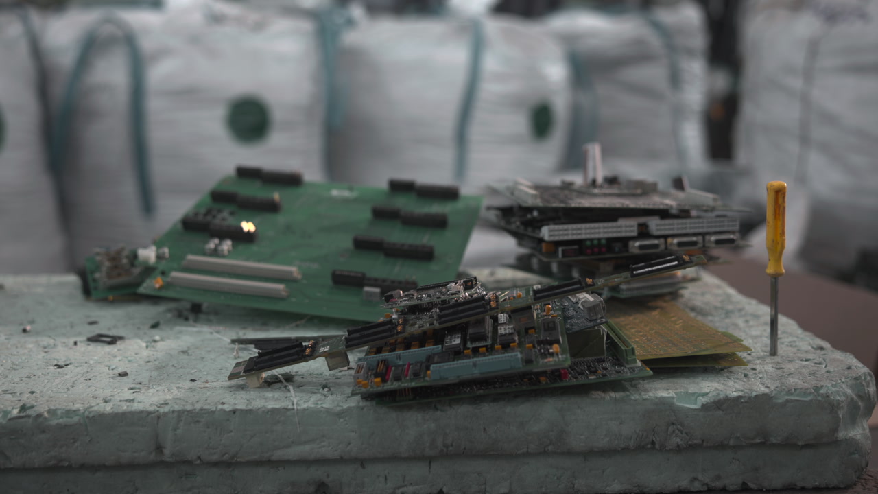 Stacked Circuit Boards On Workbench With Bulk Waste Bags In Background, Closeup Of Green Motherboards . Media