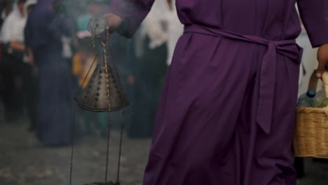 devotee swings thurible during holy week procession in the streets of antigua, guatemala