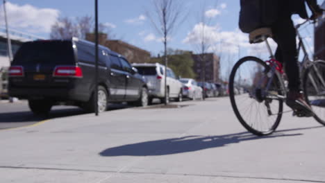 un mensajero en bicicleta poniendo su pie en los pedales, montando su bicicleta y luego pedaleando en la distancia en brookyln, nueva york