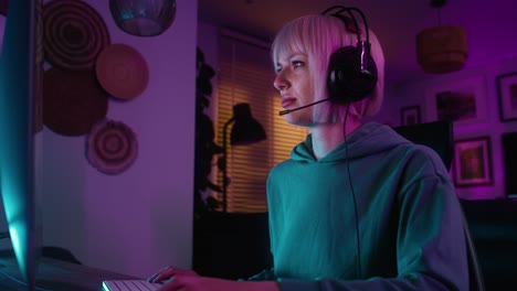 joven mujer caucásica jugando al juego por la noche en la computadora de escritorio