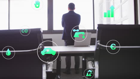 animación de iconos de concepto de energía verde contra el empresario mirando fuera de wondow en la oficina