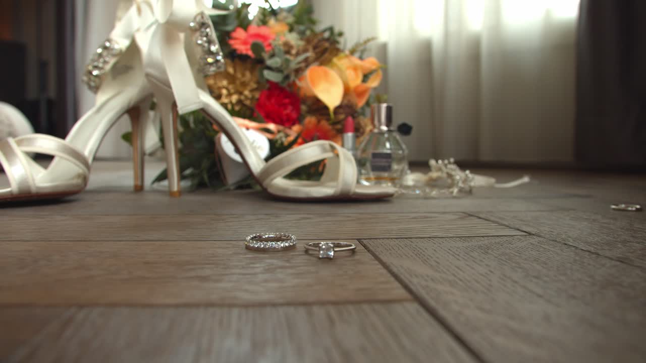 Bridge accessories and wedding ring spinning on wooden floor, close up shot