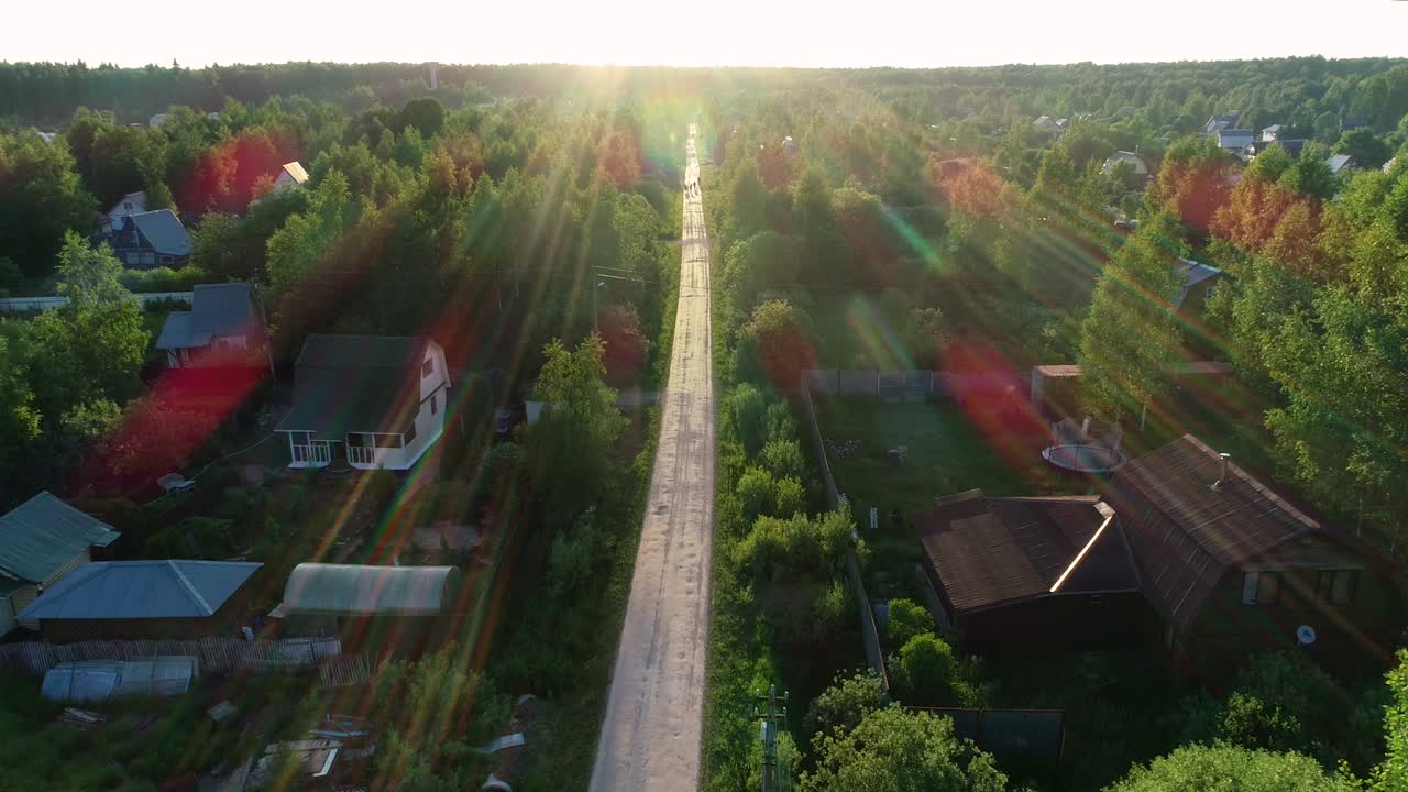 The village road. The car rides along the road between trees and houses.