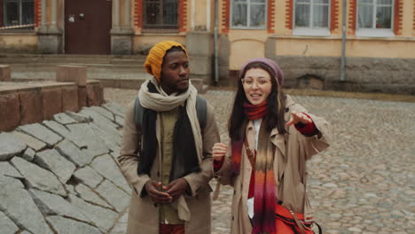 multiethnic tourist couple walking and talking in old town