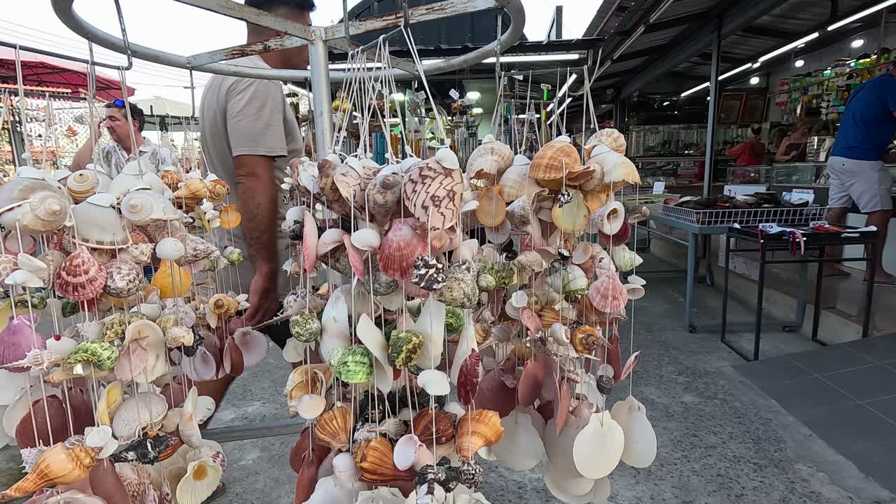 Vibrant shell decorations sway gently in a bustling Phuket market, capturing the lively atmosphere and intricate craftsmanship