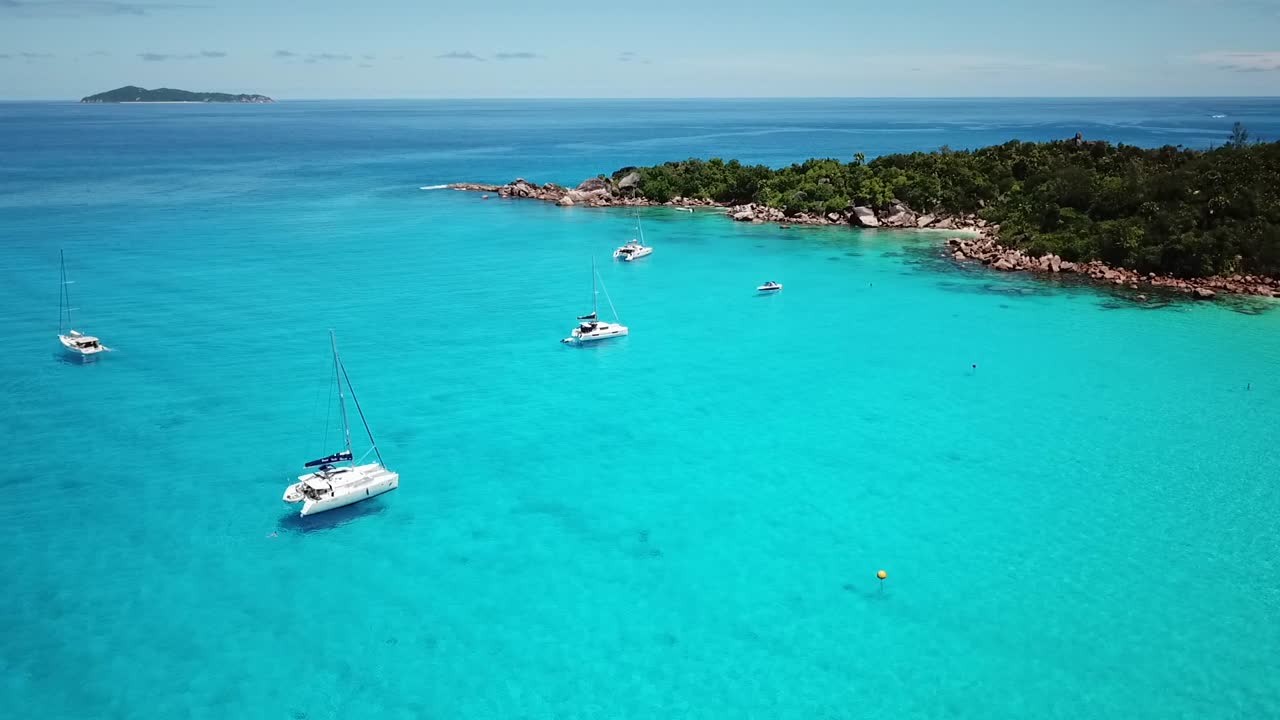 Slomo drone shot of the quiet anchorage with boats on the Praslin island, Seychelles. Flying bird.