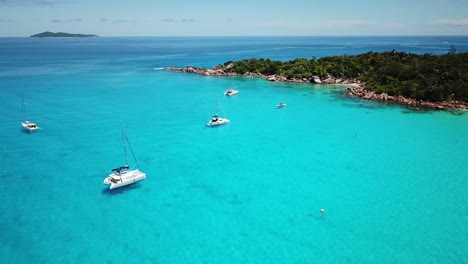 slomo drone shot of the quiet anchorage with boats on the praslin island, seychelles. flying bird.