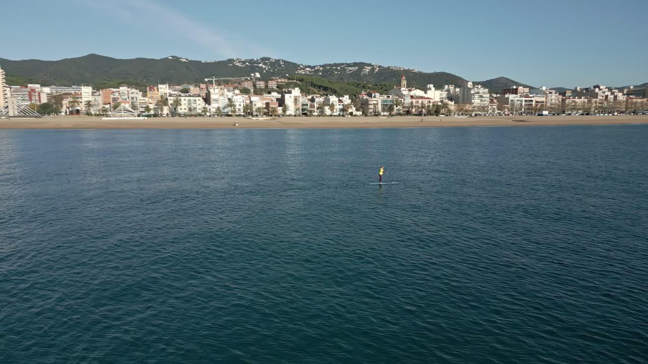 orbita sobre un surf de remo en solitario con una vista de la ciudad al fondo, en un soleado día de otoño