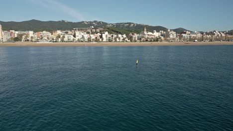 Orbita-Sobre-Un-Surf-De-Remo-En-Solitario-Con-Una-Vista-De-La-Ciudad-Al-Fondo,-En-Un-Soleado-Día-De-Otoño