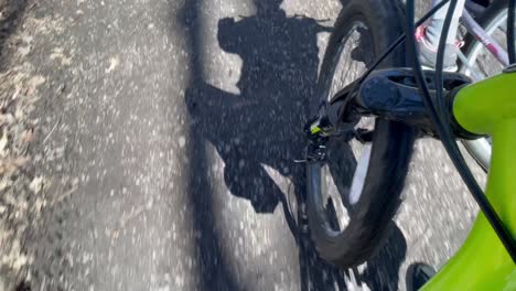 biking though path in forest on bike trail with closeup of front bike tire and passing path - mountain bike