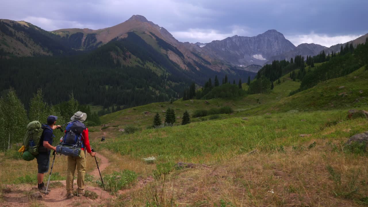 Friends backpacking camping hiker hiking trail enjoying landscape view of Capitol Peak 14er wilderness trailhead Colorado cloudy afternoon grey skies summer Rocky Mountains Elk Range Aspen Trees