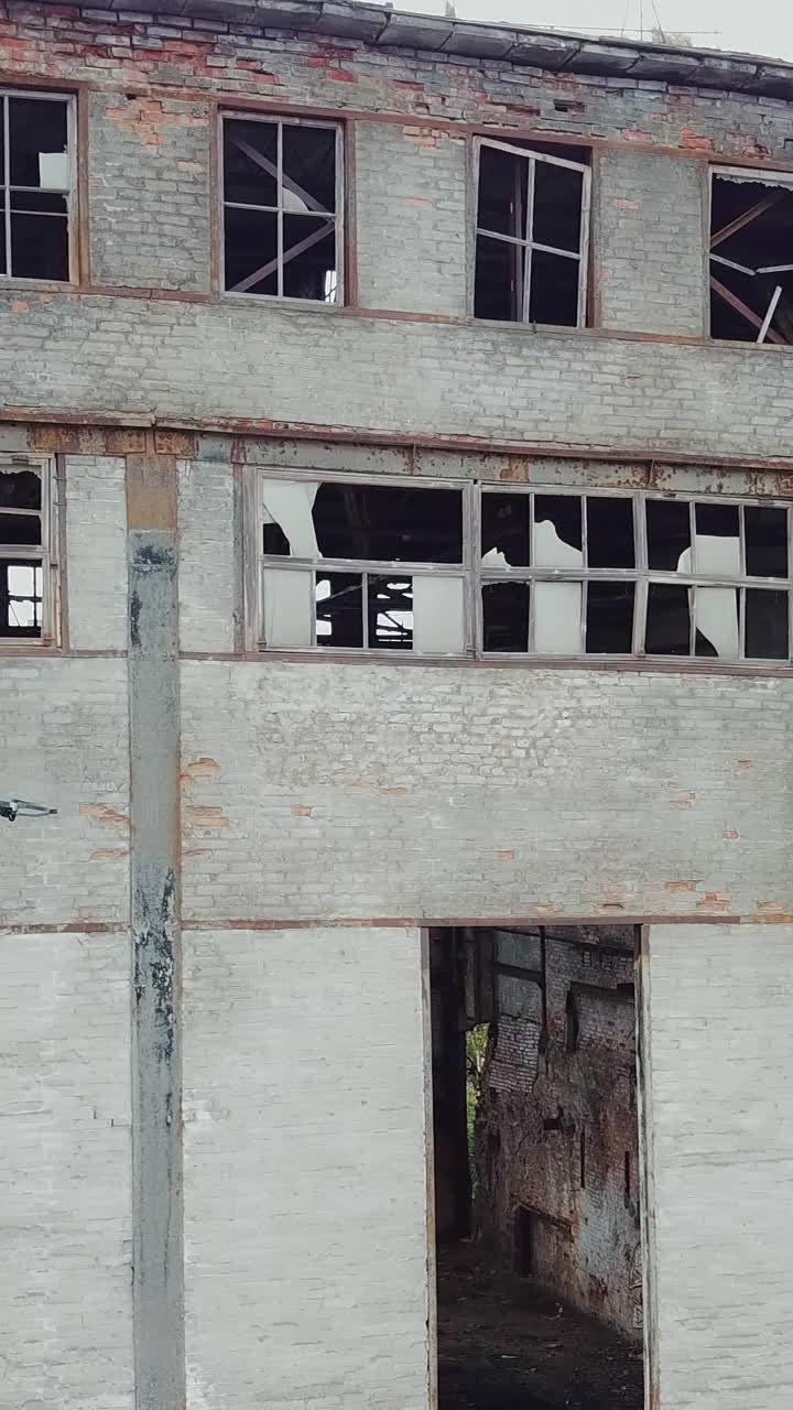 Aerial view of abandoned industrial buildings. Drone flies over an abandoned factory.. Vertical video