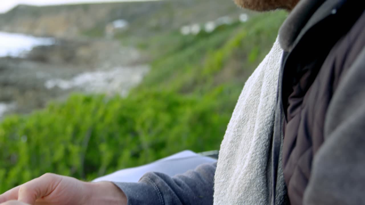 해변 4k 근처에서 휴대 전화로 문자 메시지를 보내는 중간 성인 백인 남자의 측면 뷰