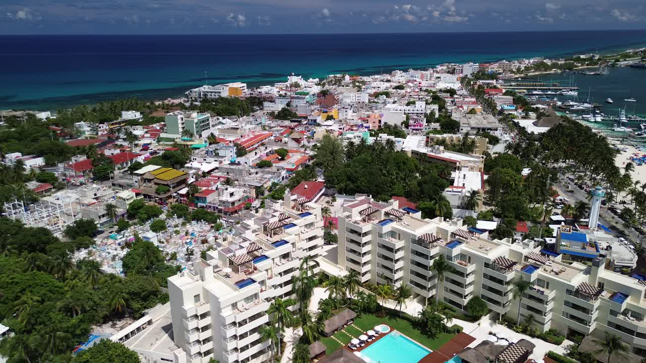 푸른 물, 활기찬 해안선, 색 건물과 호텔이 있는 도시 초록색을 따라 열대 도시의 공중 상승