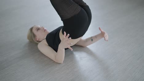 fit girl in black clothes performing contemporary. female dancer shows flowing motions, body and hands waves at white room. modern ballet dance choreography. young woman is moving smoothly