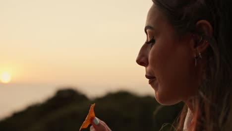 slow motion close-up shot of a female watching the sunset and eating snacks