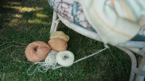 knitted, not finish sweater left on chair with yarn laying on the grass