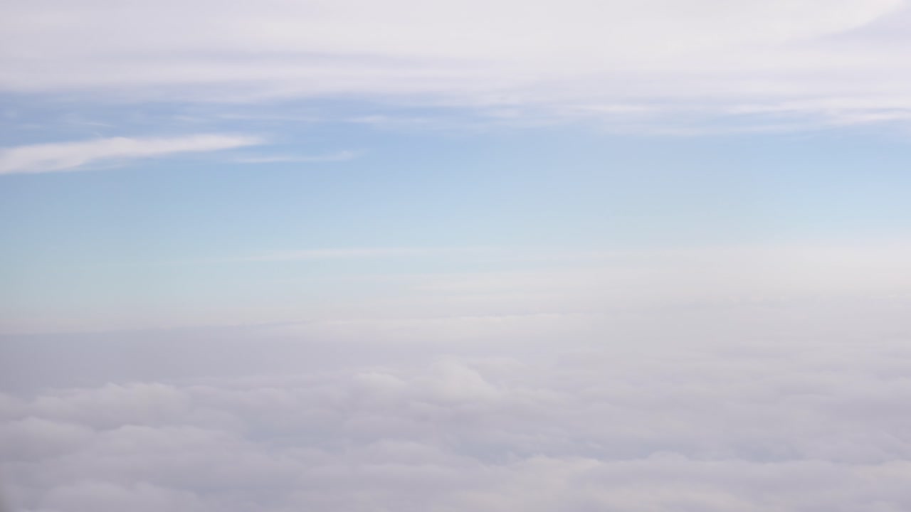 Ponto de vista de um passageiro olhando pela janela de um avião para o céu azul ensolarado e nuvens fofas.