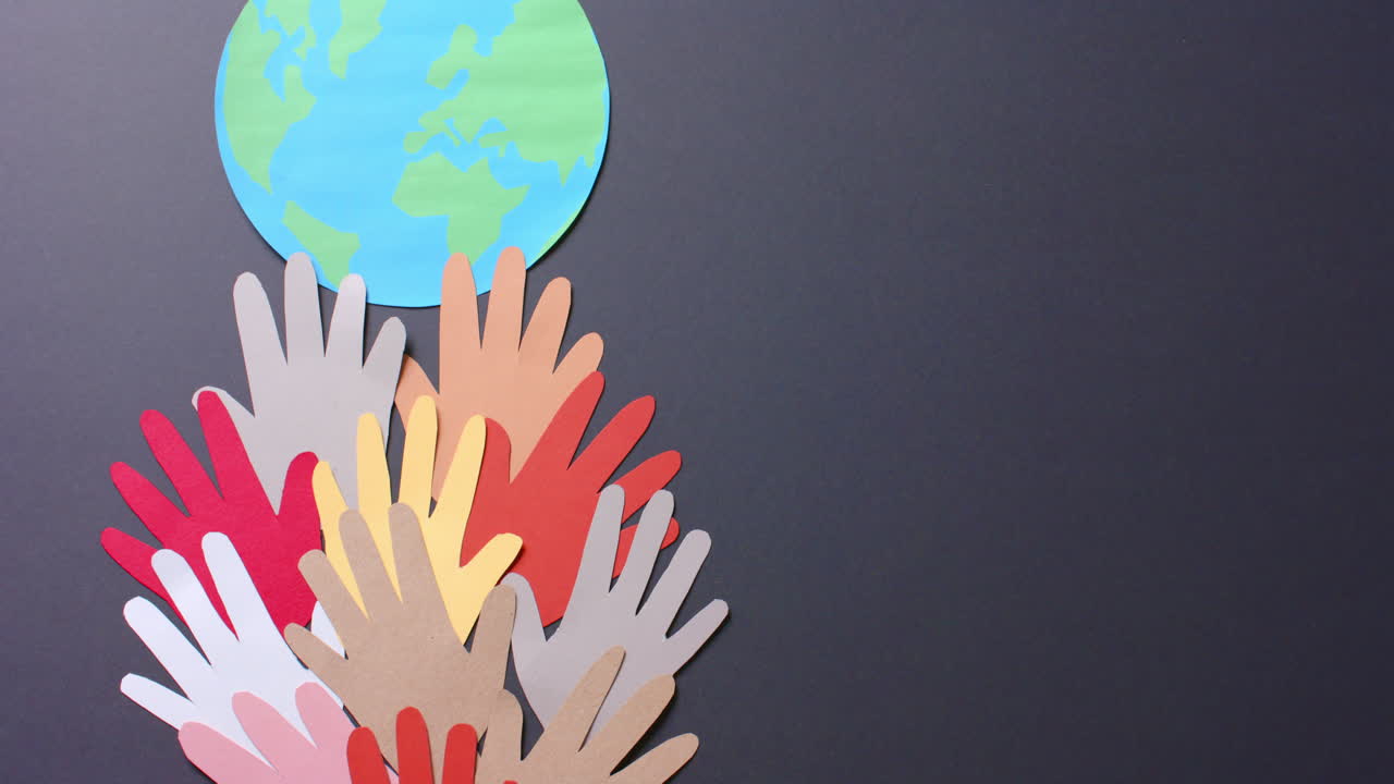 복사 공간이 있는 회색 배경에 있는 다채로운 종이로 만든 지구와 함께 손을  ⁇ 습니다.